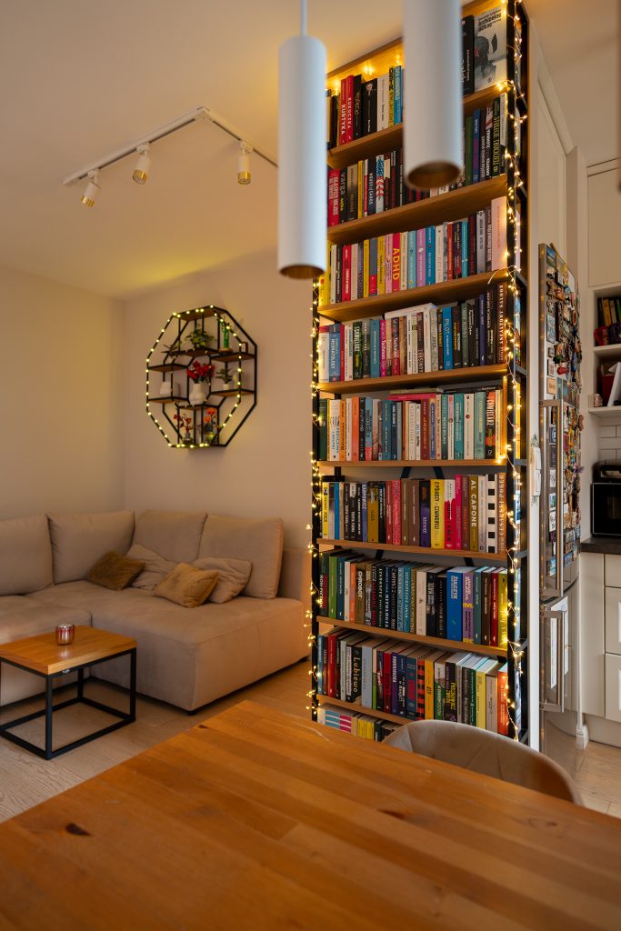 Loftowy salon – regał na książki i ciepłe oświetlenie