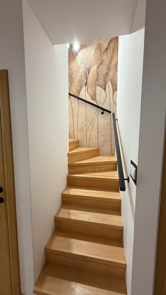 Klatka schodowa ze schodami drewnianymi i stalową poręczą